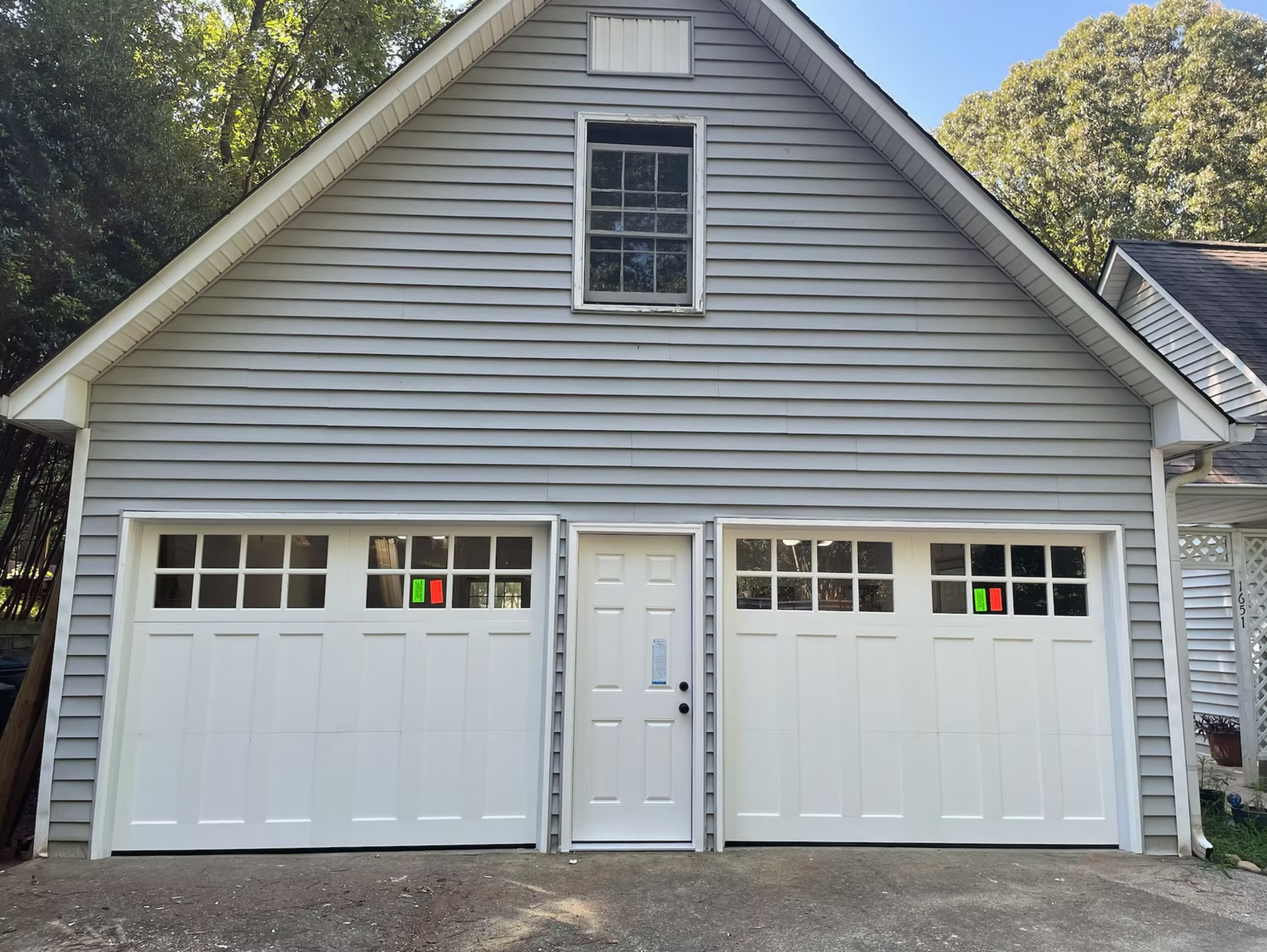 Gray residential house with two white garage doors and centered entrance door.